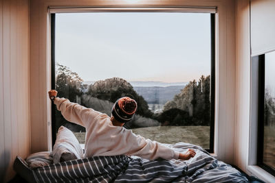 Rear view of man looking through window