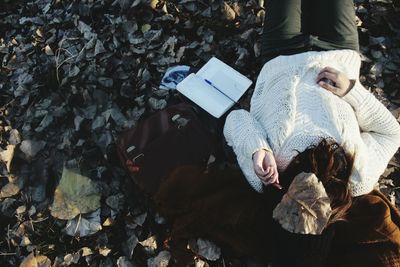 High angle view of woman covering face while lying by books on stones
