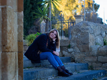 Young woman sitting on stone wall