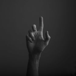 Close-up of human hand gesturing against black background