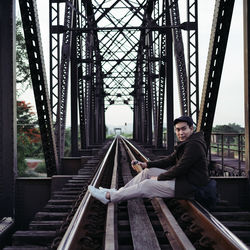 Portrait of man sitting on bridge