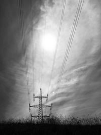 Low angle view of electricity pylon on field against sky