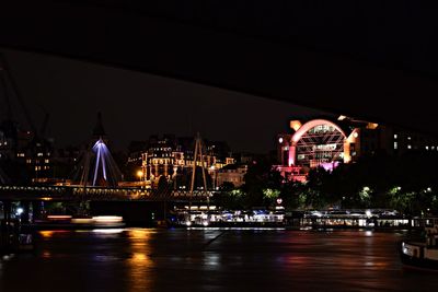 Illuminated bridge over river in city at night