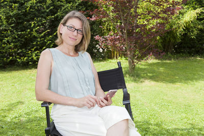 Portrait of smiling young woman sitting in park