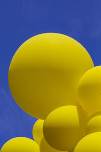 Close-up of yellow balloons against blue sky