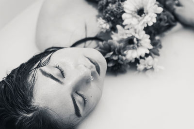 Close-up of shirtless woman with flowers in bathtub