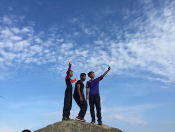 Low angle view of woman standing against cloudy sky