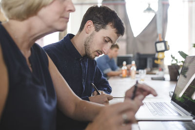 Male and female computer programmers working at desk in creative office