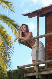 Young and beautiful woman posing leaning on bulgalow or hut in tropical paradise 