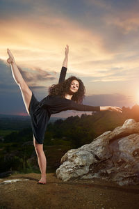 Woman standing on rock against sky during sunset