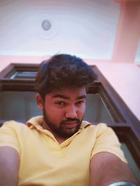 Low angle portrait of man standing by window against ceiling