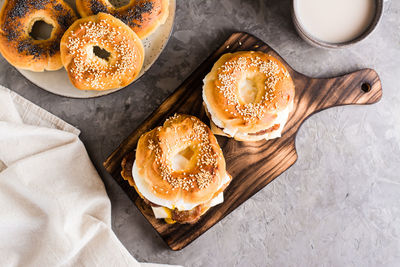 Bagels with fried meat, poached egg and cheese on a board on the table. homemade fast food. top view