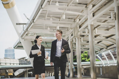 Smiling colleagues talking while walking outdoors