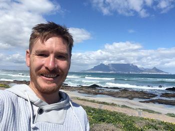 Portrait of smiling man standing at bloubergstrand against table mountain