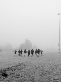 Rugby players warming up together against clear sky during foggy weather