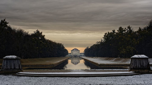 Reflection of trees in lake against cloudy sky