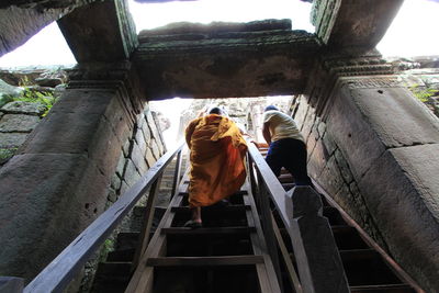 Rear view of men sitting on staircase at temple