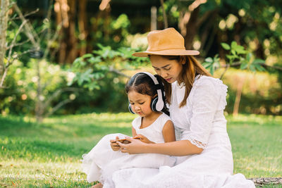 Woman sitting on grass against plants