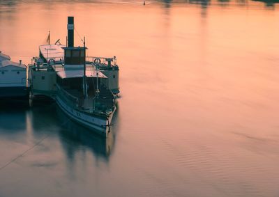 Boat moored on sea against sky during sunset