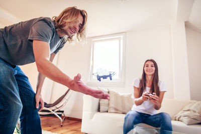 Woman using phone while sitting on sofa at home