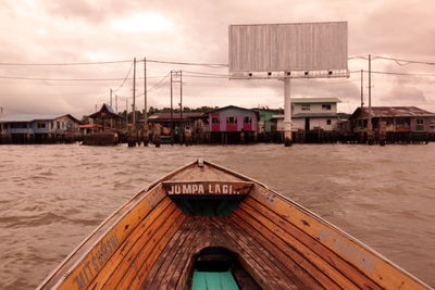 Cropped image of boat on river against stilt houses