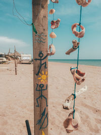 Clothes hanging on wooden post at beach against sky