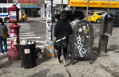 Rear view of man standing on garbage in city