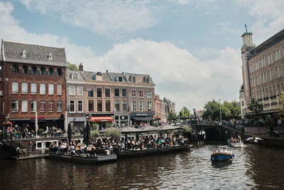 Boats in canal amidst buildings in city against sky