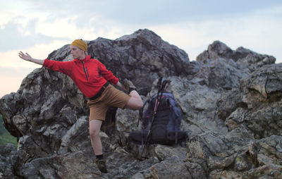 Female hiker exercising on rocks against sky