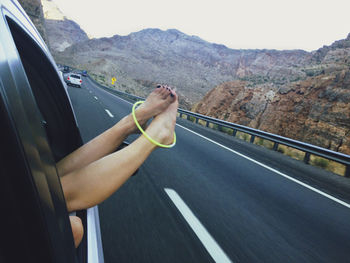 Low section of woman with feet outside car window