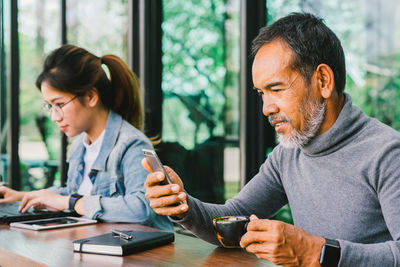 Young man using smart phone while sitting on table