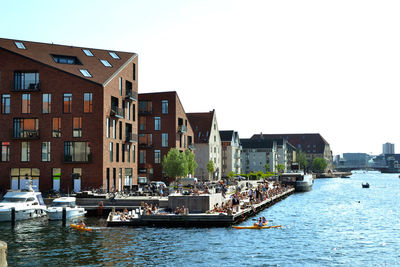 Buildings by river against clear sky