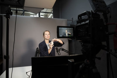 Female entrepreneur explaining about product while recording through camera at office