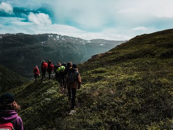 Rear view of hikers on mountain against sky