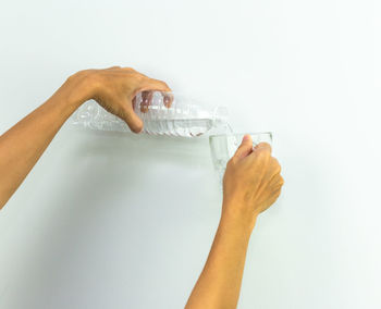Close-up of woman hand holding glass of water against white background