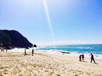 People on beach against clear sky