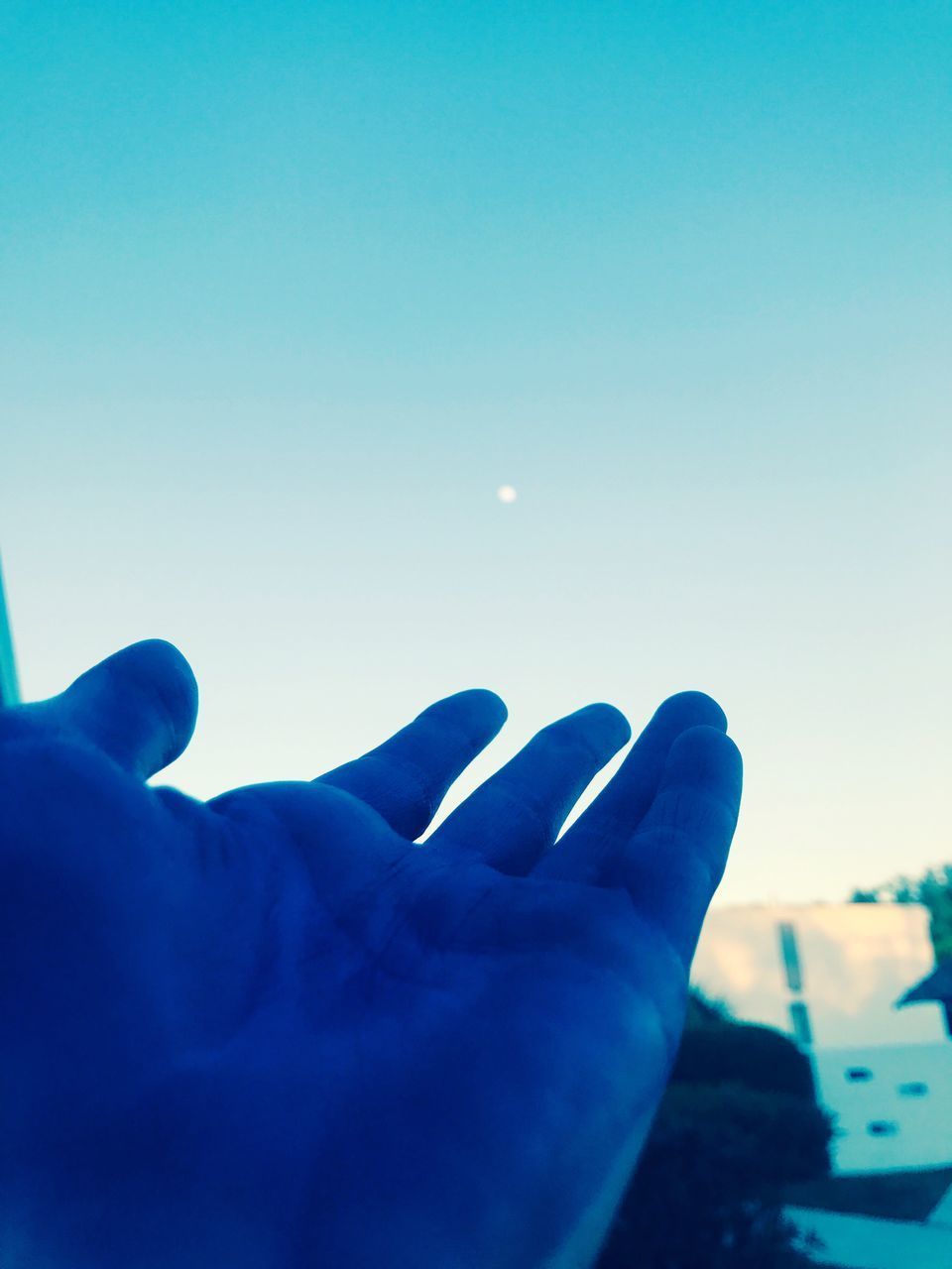 CLOSE-UP OF HAND AGAINST CLEAR SKY