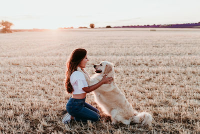 Side view of woman with dog on landscape during sunset