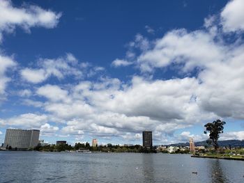 Buildings by river against sky in city