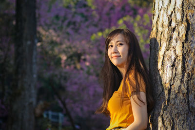 Portrait of woman standing on tree trunk