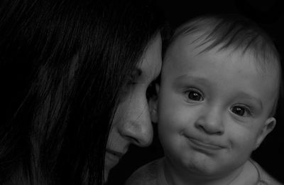 Close-up of cute boy with mother against black background