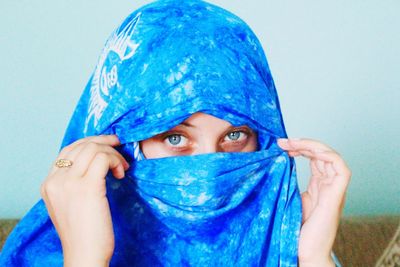 Close-up portrait of young woman against blue background