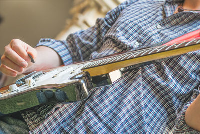 Midsection of man playing guitar