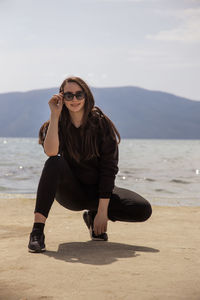 Young woman wearing sunglasses on beach against sky