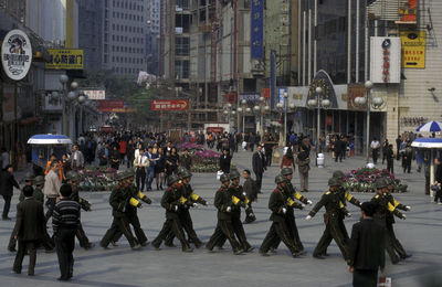 Armed forces marching on footpath in city