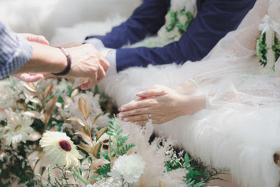 Midsection of people holding flower bouquet