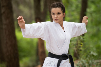 Side view of young woman with arms raised standing outdoors