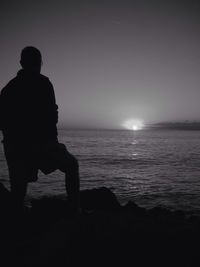 Silhouette of woman standing on beach at sunset