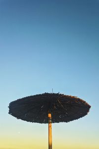 Low angle view of parasol against clear blue sky