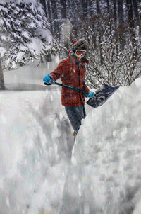 Person in warm cloth cleaning snow during snowfall